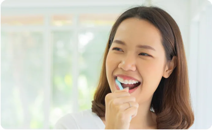 A smiling woman brushing her teeth
