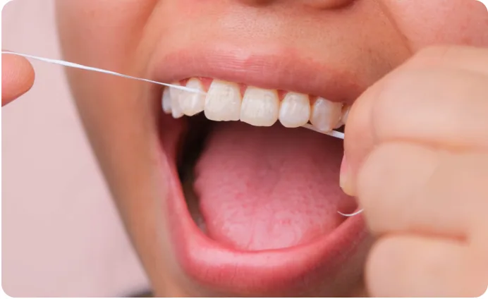 Close-up of a person flossing between their teeth