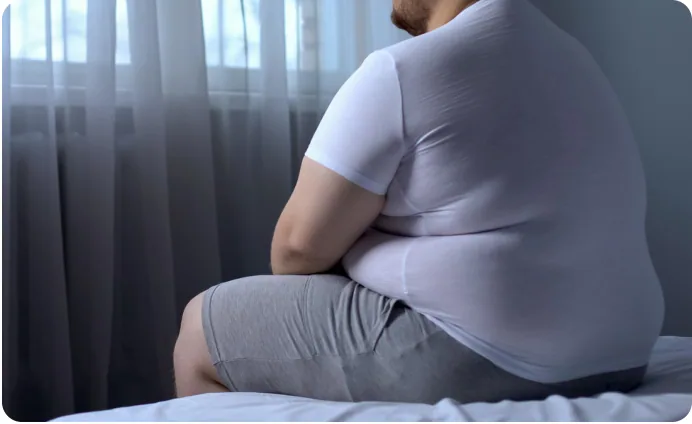 A man sitting on the edge of a bed, seen from behind