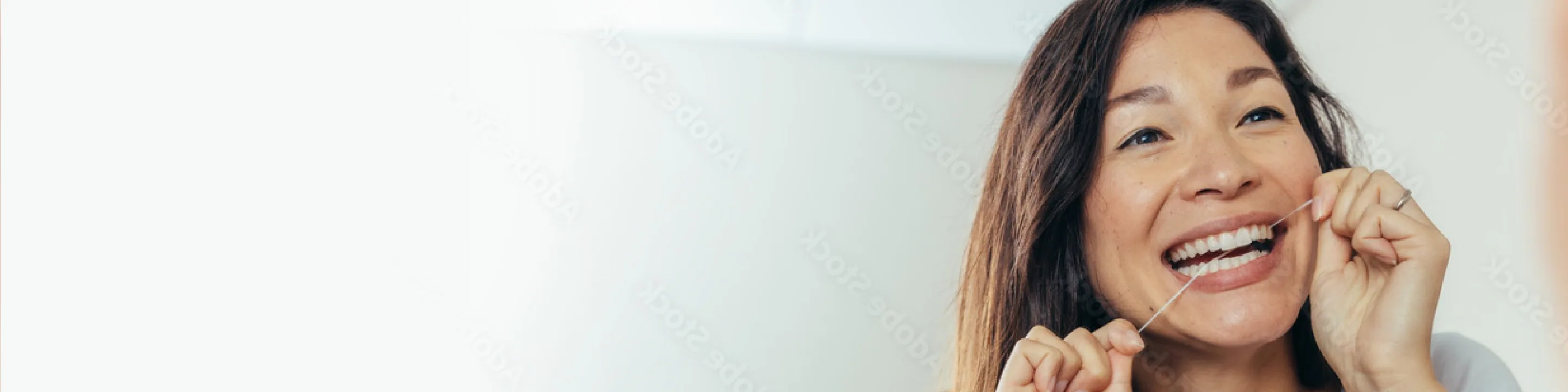 A smiling woman flossing her teeth
