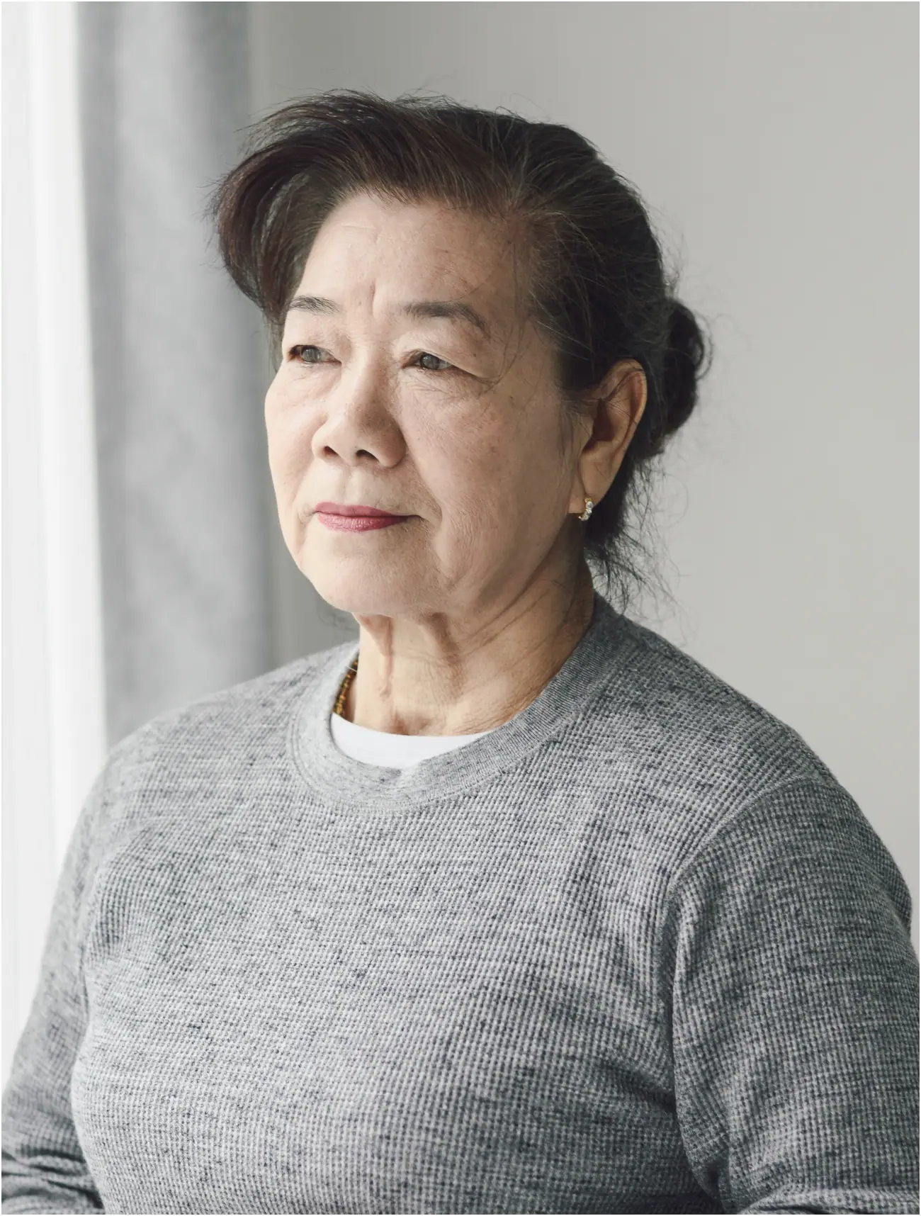An older woman looking thoughtfully out of a window